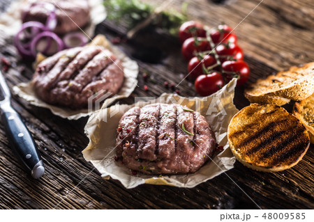 Raw burgers on wooden table with herbs and spices. 48009585