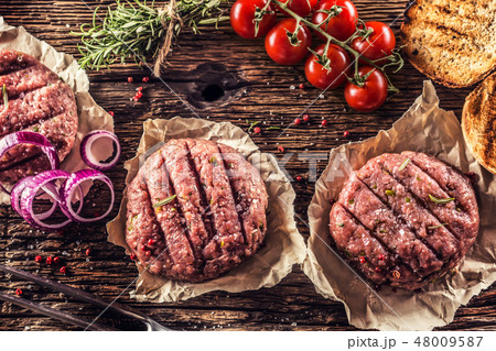 Raw burgers on wooden table with herbs and spices. 48009587