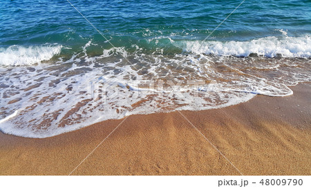 Sea wave with white foam in the coastal sand 48009790