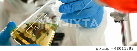 Male chemist look at microscope hold test tube 48011595