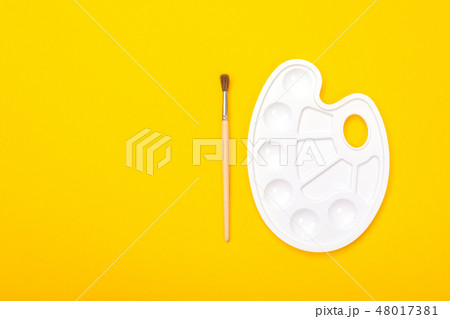 Paint brush and palette lie isolated on yellow background Paint brush and palette lie isolated on yellow background 48017381
