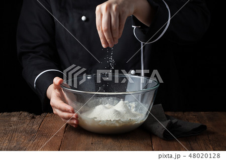 Chef hands sprinkles sea salt on raw dough. Chef hands sprinkles sea salt on raw dough. 48020128