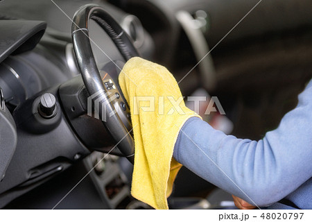 Man cleaning steering wheel with yellow microfiber cloth. Man cleaning steering wheel with yellow microfiber cloth. 48020797