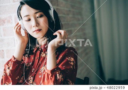 ヘッドホンで音楽を聞く赤いワンピースの女性の写真素材