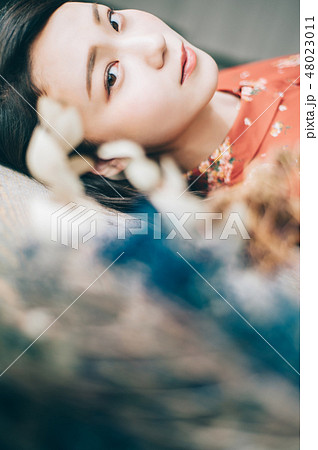 床に寝転ぶ赤いワンピースの女性 48023011