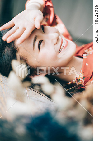 床に寝転ぶ赤いワンピースの女性 48023016