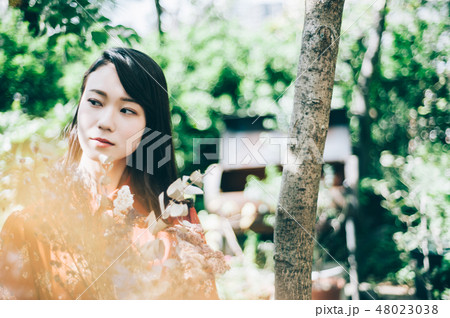 庭で花束を持つ赤いワンピースの女性 庭で花束を持つ赤いワンピースの女性 48023038