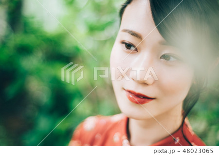 庭にいる髪の毛をアップにした赤いワンピースの女性の写真素材 庭にいる髪の毛をアップにした赤いワンピースの女性の写真素材