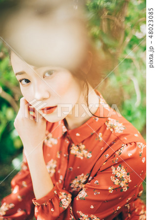 庭にいる髪の毛をアップにした赤いワンピースの女性 48023085