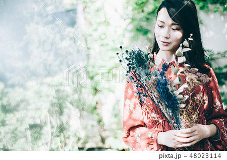 庭で花束を持つ赤いワンピースの女性 庭で花束を持つ赤いワンピースの女性 48023114