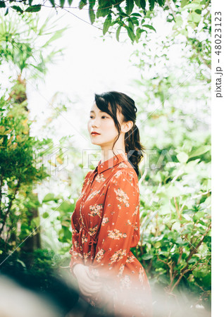 庭にいる髪の毛をアップにした赤いワンピースの女性 48023123