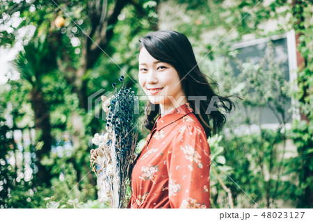 庭で花束を持つ赤いワンピースの女性 庭で花束を持つ赤いワンピースの女性 48023127