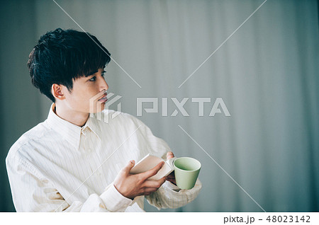 窓際で本を読む白いシャツの男性 48023142