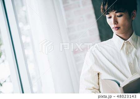 窓際で本を読む白いシャツの男性 48023143