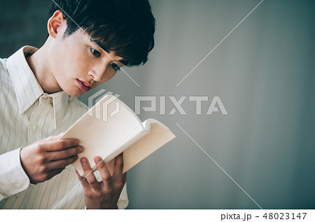窓際で本を読む白いシャツの男性 48023147