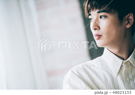 窓際で本を読む白いシャツの男性 48023155