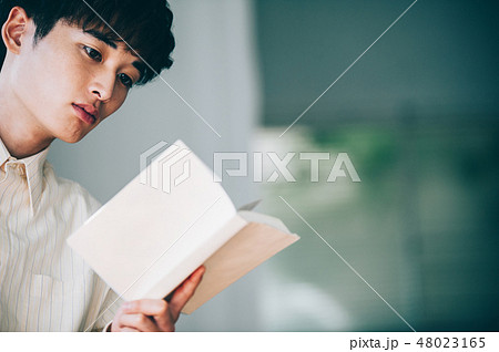 窓際で本を読む白いシャツの男性 48023165