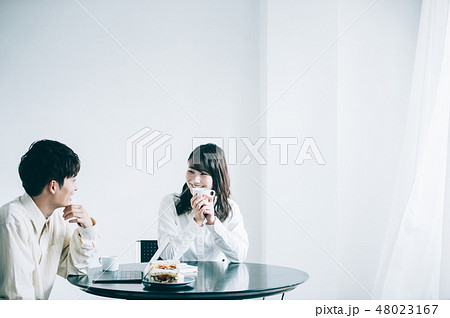 休憩室でマグカップを手に談笑する男女 48023167