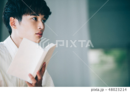 窓際で本を読む白いシャツの男性 48023214