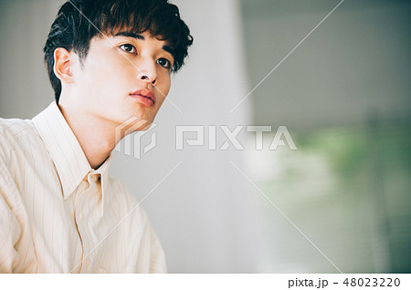 窓際で本を読む白いシャツの男性 48023220