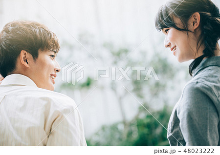 ベランダに腰掛けて談笑する男女 48023222