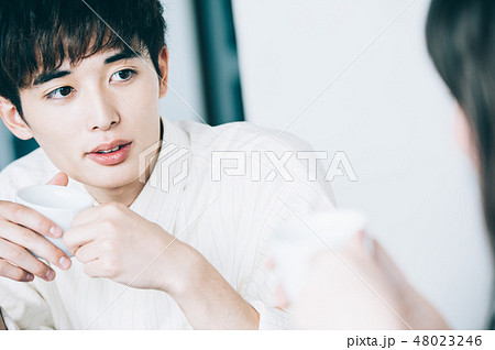 休憩室でマグカップを手に談笑する男女 48023246