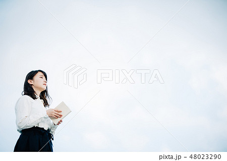 屋上で本を読む白いシャツの女性 48023290