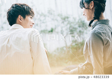 ベランダに腰掛けて談笑する男女 48023339