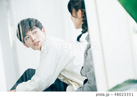 窓際に座って談笑する男女 48023351