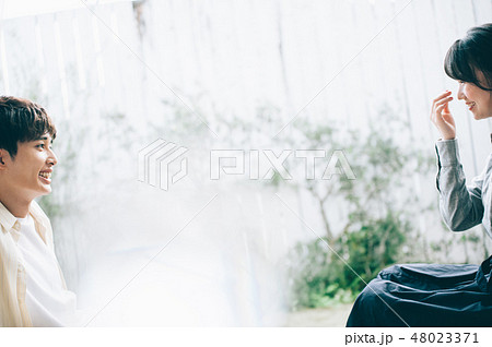 ベランダに腰掛けて談笑する男女 48023371