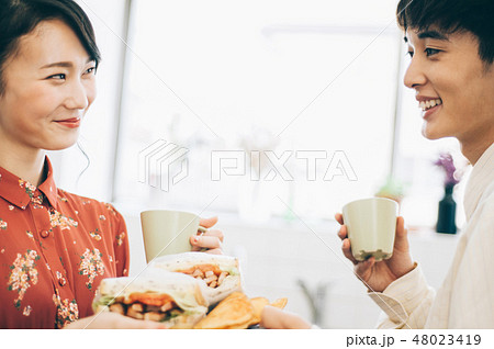キッチンでサンドイッチを手渡す男女 キッチンでサンドイッチを手渡す男女 48023419