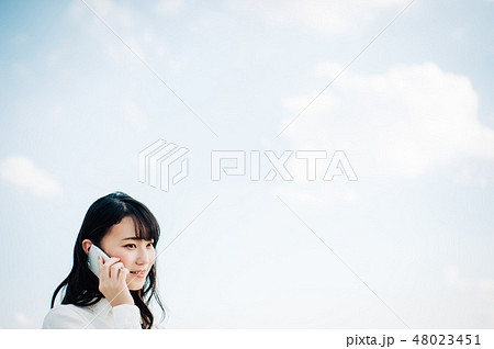 屋上で電話する白いシャツを着た女性 48023451