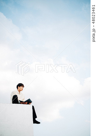 屋上に座ってノートパソコンを開く男性の写真素材