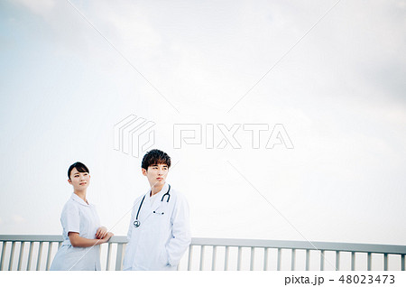 屋上で手すりにもたれる白衣を着た男女 48023473