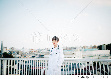 屋上で手すりにもたれる白衣を着た男性 屋上で手すりにもたれる白衣を着た男性 48023484