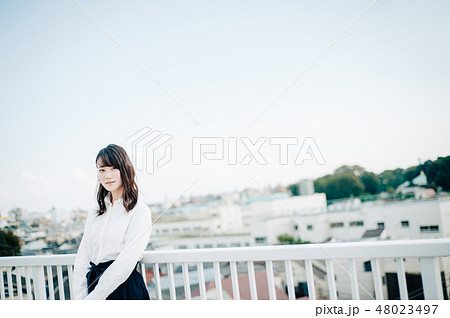 屋上に立つ白いシャツを着た女性 48023497