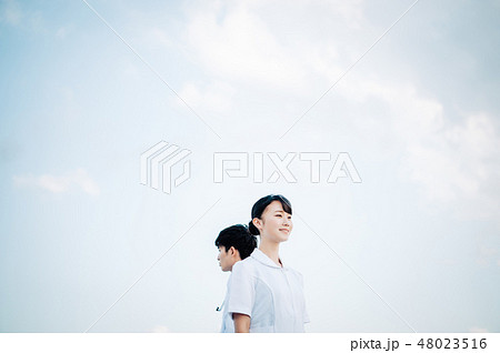 屋上に立つ白衣を着た背中合わせの男女 48023516