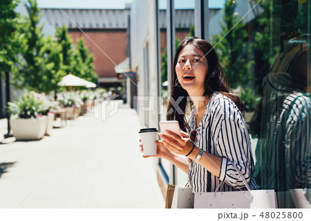 woman standing by fashion store window display woman standing by fashion store window display 48025800