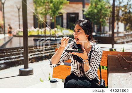 asian lady having lunch outdoor on bench chair 48025806
