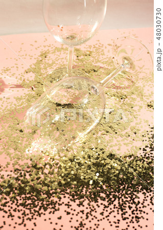 Empty glass goblets for champagne in golden confetti on the table. Festive background. Party concept Empty glass goblets for champagne in golden confetti on the table. Festive background. Party concept 48030730