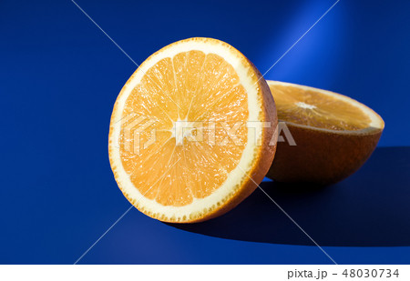 Two halves of ripe orange on a blue background in bright sunlight Two halves of ripe orange on a blue background in bright sunlight 48030734