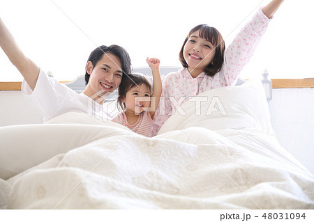 ベッドに入る若い家族の写真素材 ベッドに入る若い家族の写真素材