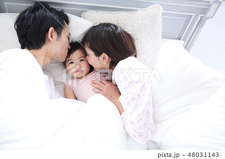 ベッドに入る若い家族の写真素材 ベッドに入る若い家族の写真素材