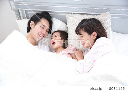 ベッドに入る若い家族の写真素材 ベッドに入る若い家族の写真素材
