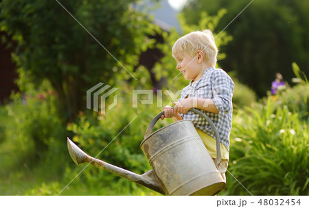 Cute toddler boy watering plants in the garden 48032454