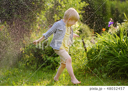 Funny little boy playing with garden sprinkler 48032457