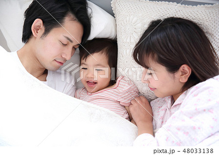 ベッドに入る若い家族 48033138