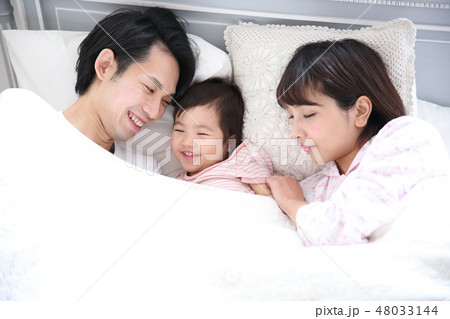 ベッドに入る若い家族 48033144