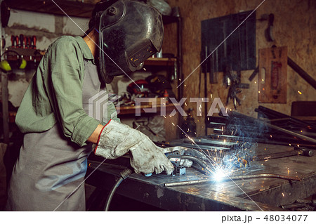Busy and serious craftswoman grinding timbers with special machine. 48034077