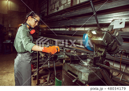 Busy and serious craftswoman grinding timbers with special machine. 48034179